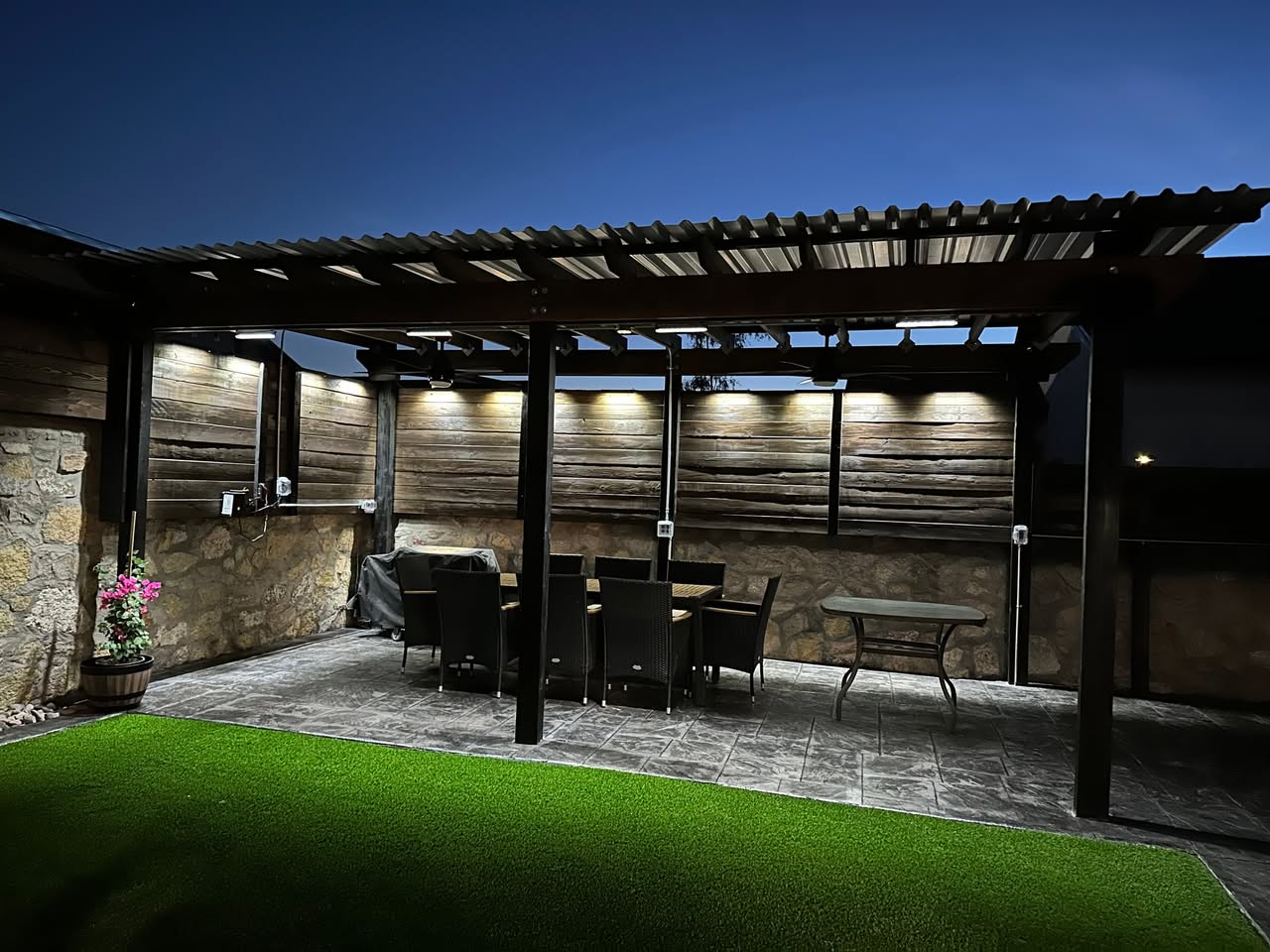 Interior of a custom stained-wood pavilion in San Antonio with tongue-and-groove ceiling, large ceiling fan, mounted TV and linear fireplace